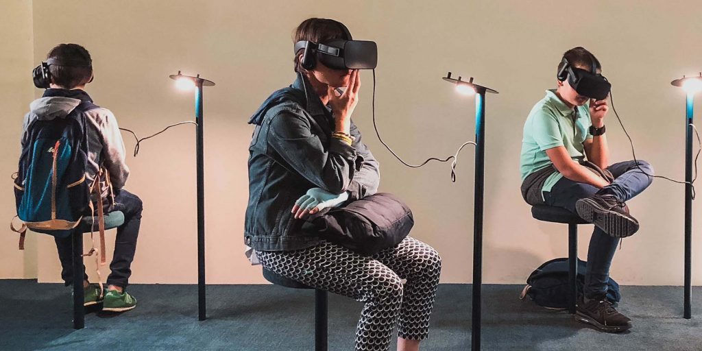 three young students sit on stools while searing Metalab VR headsets
